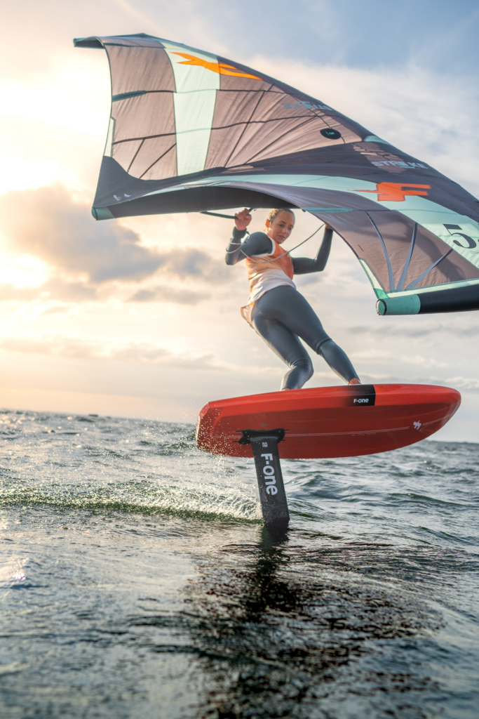 wingfoiling, dziewczyna trenujące windfoling, zachód słońca, morze.